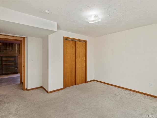 unfurnished bedroom featuring light carpet, a textured ceiling, and a closet