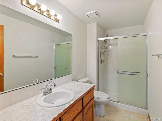 bathroom with vanity, tasteful backsplash, toilet, and a shower with door