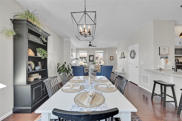 dining space featuring sink, ceiling fan with notable chandelier, and dark wood-type flooring