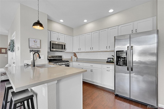 kitchen featuring sink, white cabinetry, dark hardwood / wood-style floors, pendant lighting, and stainless steel appliances