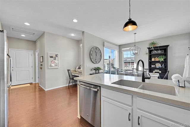 kitchen with sink, white cabinetry, decorative light fixtures, appliances with stainless steel finishes, and dark hardwood / wood-style flooring