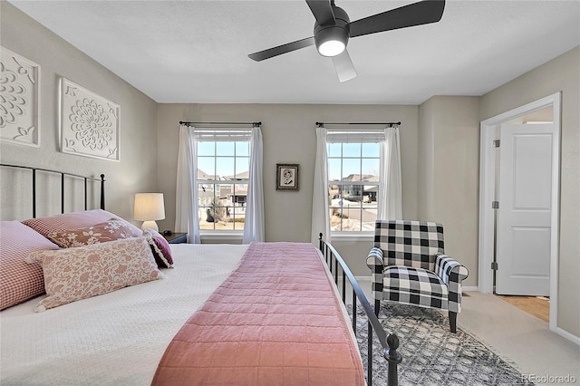 bedroom with multiple windows, light carpet, a textured ceiling, and ceiling fan