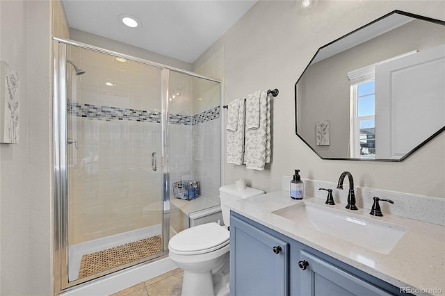 bathroom featuring vanity, a shower with door, tile patterned floors, and toilet