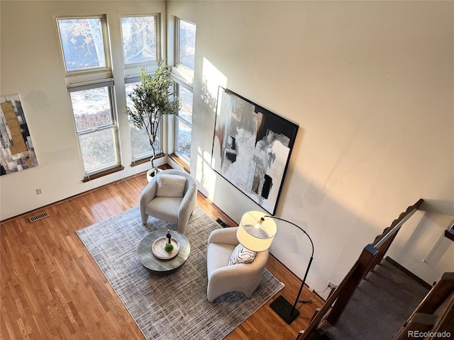 living area with a healthy amount of sunlight, a high ceiling, and hardwood / wood-style floors