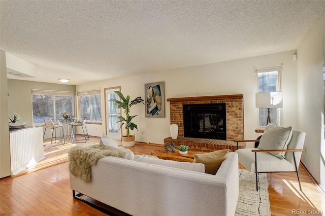 living room with a textured ceiling, light wood-type flooring, and a fireplace