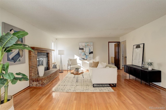 living room featuring a fireplace, a textured ceiling, and light hardwood / wood-style flooring