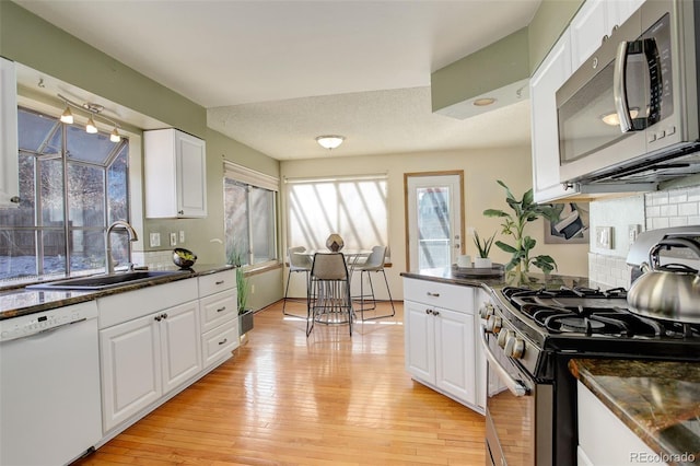 kitchen with stainless steel appliances, white cabinets, a textured ceiling, light hardwood / wood-style flooring, and sink