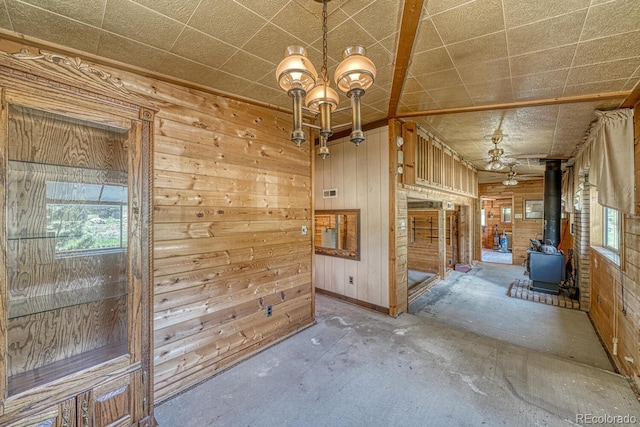 6130 County Road 328, Westcliffe, CO 81252 - spare room with a wood stove, a chandelier, wooden walls, and concrete flooring