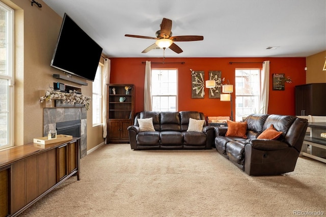 living area with a ceiling fan, a healthy amount of sunlight, light carpet, and a tile fireplace