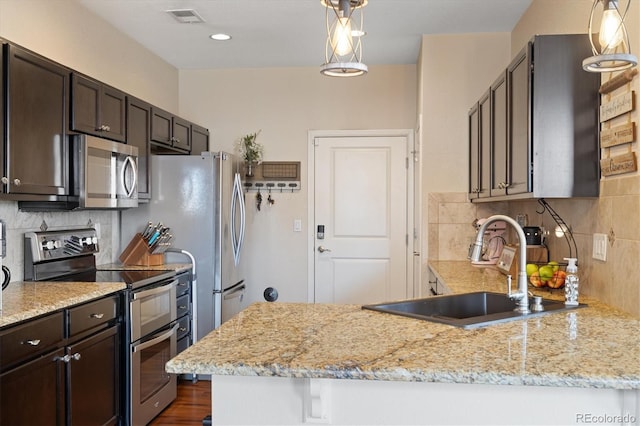 kitchen featuring stainless steel appliances, dark brown cabinetry, a sink, and tasteful backsplash