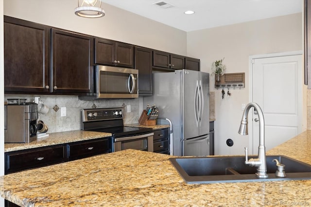 kitchen featuring dark brown cabinetry, a sink, stainless steel appliances, decorative backsplash, and visible vents