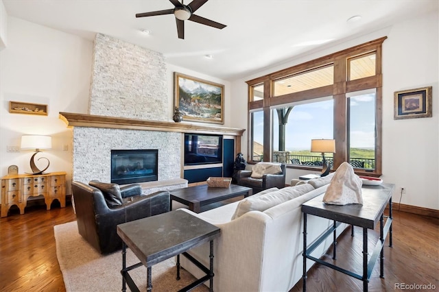 6194 Falcon Ridge Way, Morrison, CO 80465 - living area featuring a stone fireplace, ceiling fan, wood finished floors, and baseboards