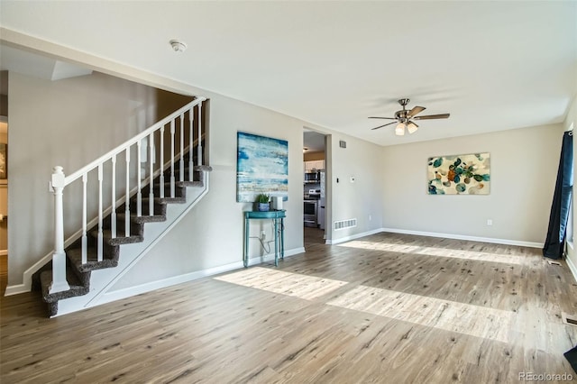 unfurnished living room featuring ceiling fan and hardwood / wood-style flooring