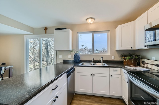 kitchen featuring hardwood / wood-style flooring, sink, white cabinets, and appliances with stainless steel finishes