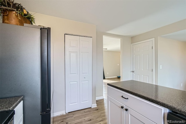 kitchen with light hardwood / wood-style floors, white cabinetry, range, and stainless steel refrigerator