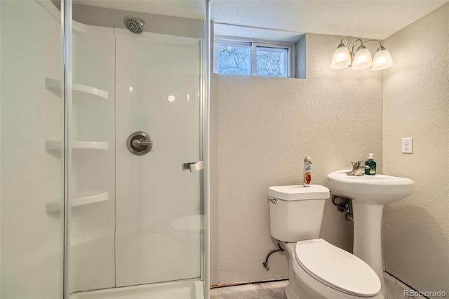 bathroom with toilet, a shower with door, and sink