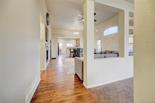 corridor featuring wood finished floors, visible vents, and baseboards