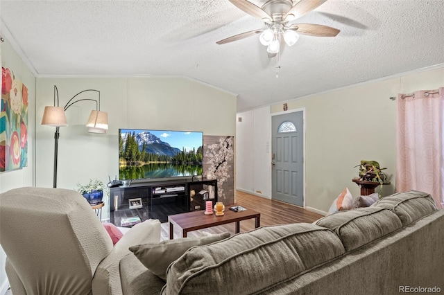 living room with a textured ceiling, ornamental molding, hardwood / wood-style floors, and vaulted ceiling