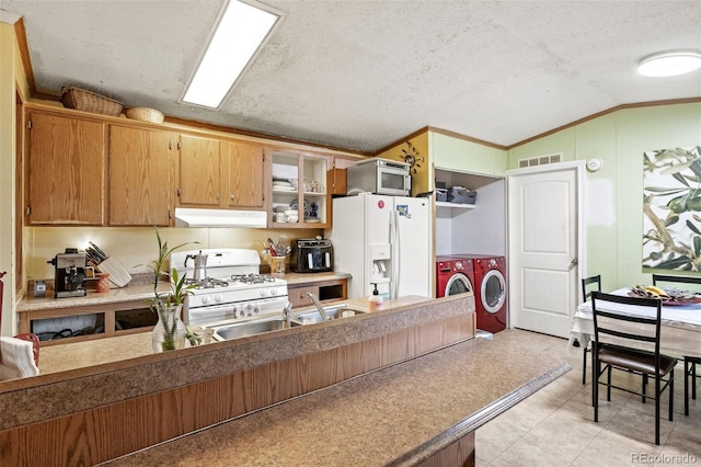 kitchen featuring washer and dryer, white appliances, vaulted ceiling, ornamental molding, and sink