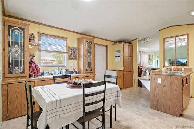 dining room featuring lofted ceiling, sink, and crown molding