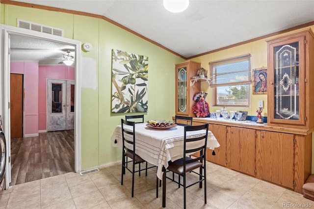 dining area with crown molding, light tile patterned floors, and lofted ceiling