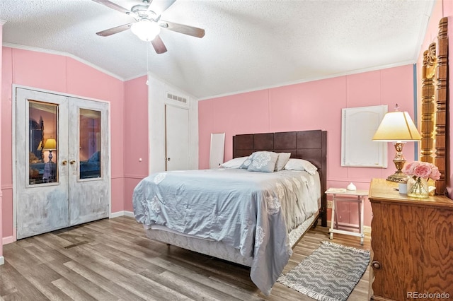 bedroom with ceiling fan, a textured ceiling, wood-type flooring, and vaulted ceiling