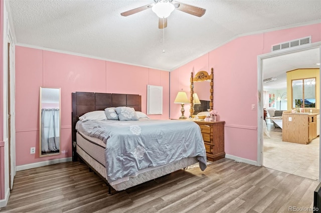 bedroom with ceiling fan, ornamental molding, lofted ceiling, and hardwood / wood-style floors