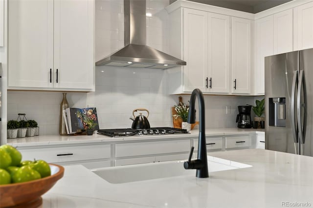 kitchen with white cabinetry, wall chimney exhaust hood, and tasteful backsplash