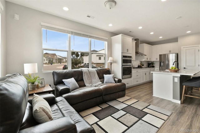 living room with visible vents, recessed lighting, and light wood-style floors