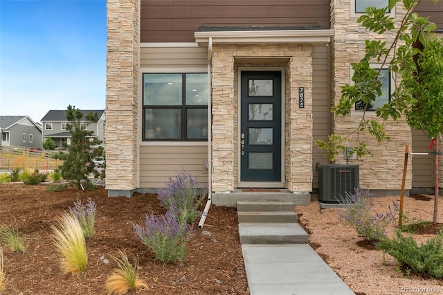 doorway to property featuring stone siding and central AC