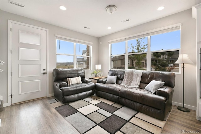 living area with visible vents, baseboards, and wood finished floors