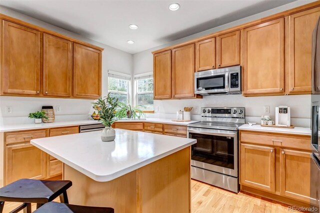 kitchen featuring a kitchen bar, light countertops, light wood-style floors, stainless steel appliances, and recessed lighting