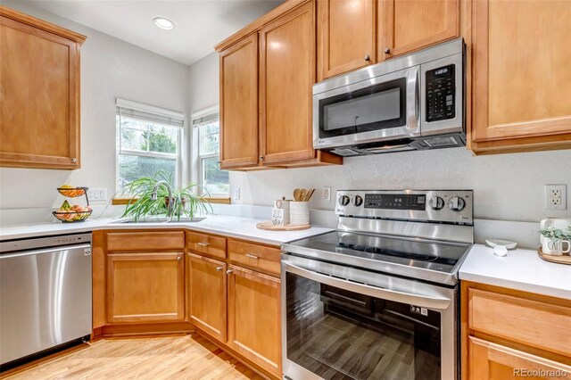 kitchen featuring light wood-type flooring, light countertops, recessed lighting, a sink, and stainless steel appliances