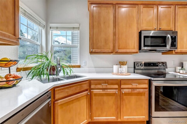 kitchen featuring a sink, appliances with stainless steel finishes, brown cabinets, and light countertops