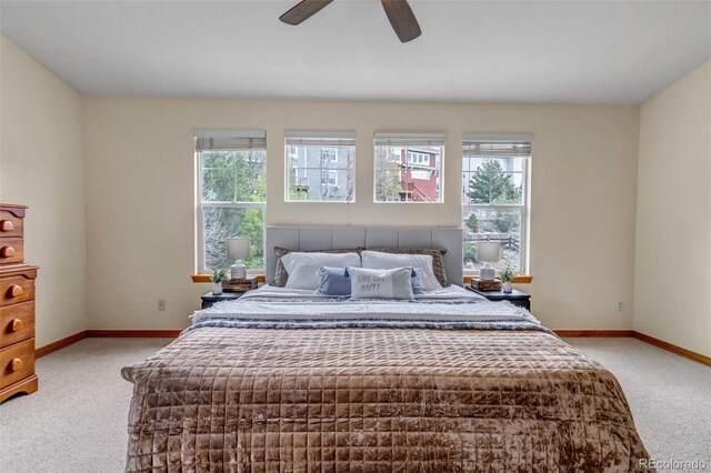 bedroom featuring baseboards, light colored carpet, and multiple windows