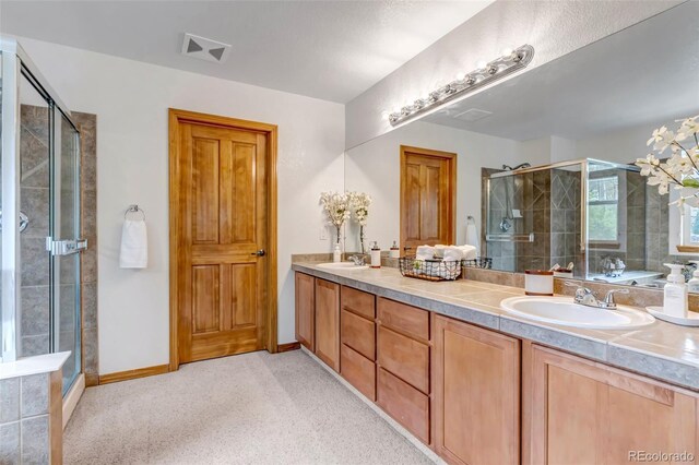 bathroom with double vanity, a sink, visible vents, and a shower stall