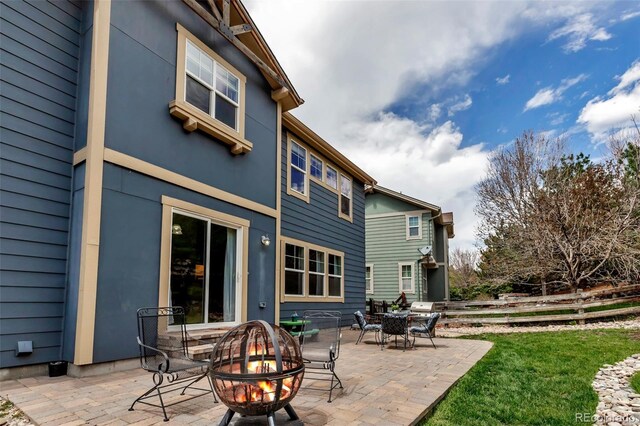 back of house with a fire pit, fence, stucco siding, a patio area, and a lawn