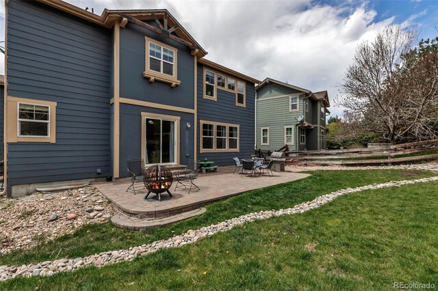 back of house featuring a lawn, a fire pit, fence, and a patio