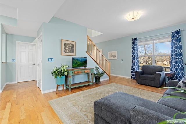 living room featuring stairs, wood finished floors, and baseboards