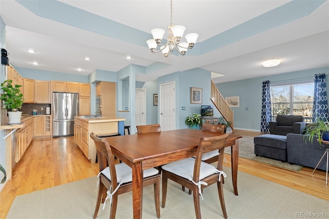 dining area featuring light wood-style floors, stairway, baseboards, and an inviting chandelier