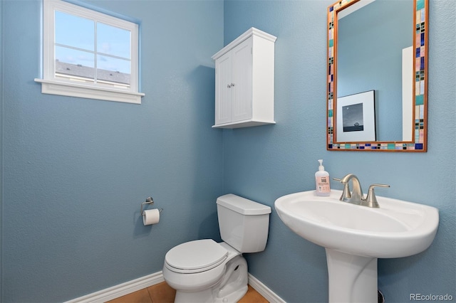 half bathroom featuring tile patterned flooring, toilet, and baseboards