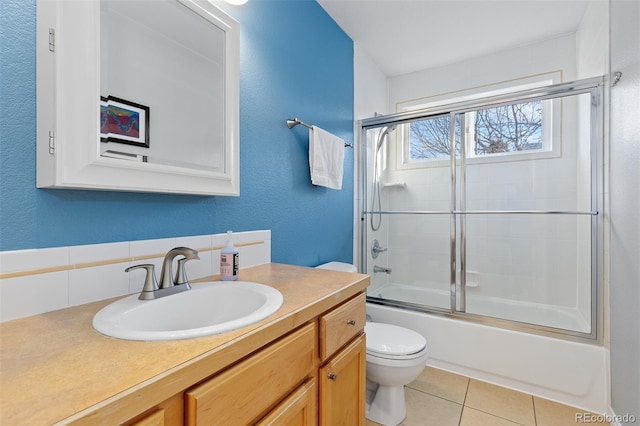 full bathroom with enclosed tub / shower combo, a textured wall, tile patterned flooring, toilet, and vanity