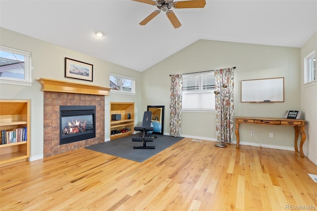 living area featuring built in features, a fireplace, lofted ceiling, wood finished floors, and baseboards