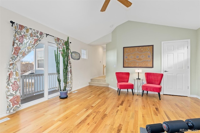 living area with visible vents, wood finished floors, stairs, vaulted ceiling, and a healthy amount of sunlight