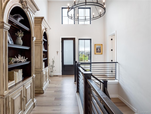 interior space featuring a notable chandelier, light hardwood / wood-style flooring, and a high ceiling