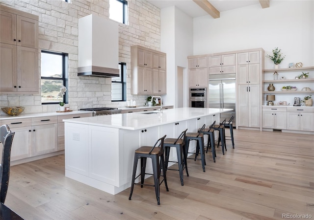 kitchen with stainless steel appliances, a center island with sink, a breakfast bar, and light wood-type flooring