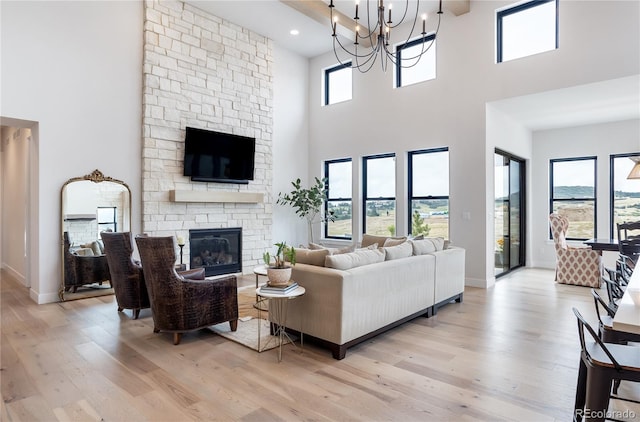 living room featuring a wealth of natural light, light hardwood / wood-style floors, a chandelier, and a fireplace