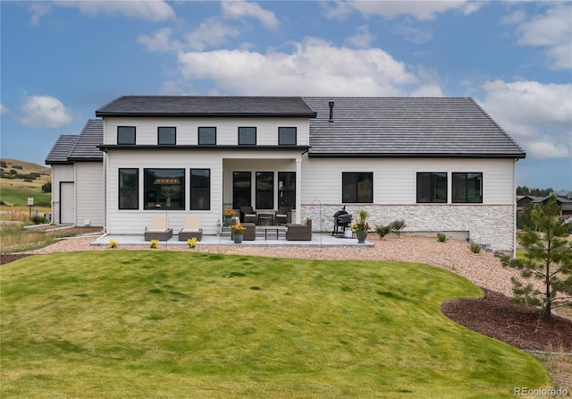 rear view of house with a patio, an outdoor living space, and a lawn