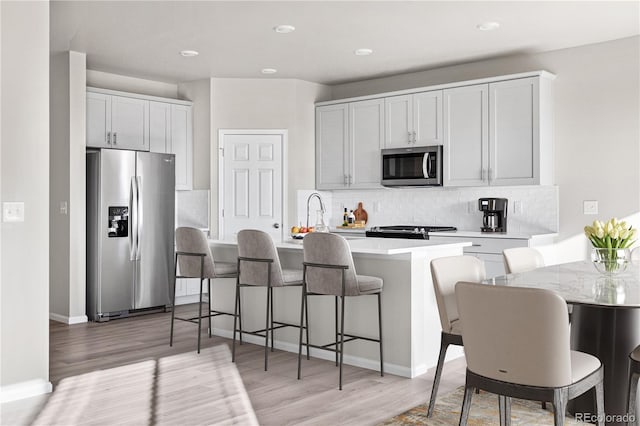 kitchen featuring appliances with stainless steel finishes, sink, a breakfast bar area, white cabinets, and decorative backsplash