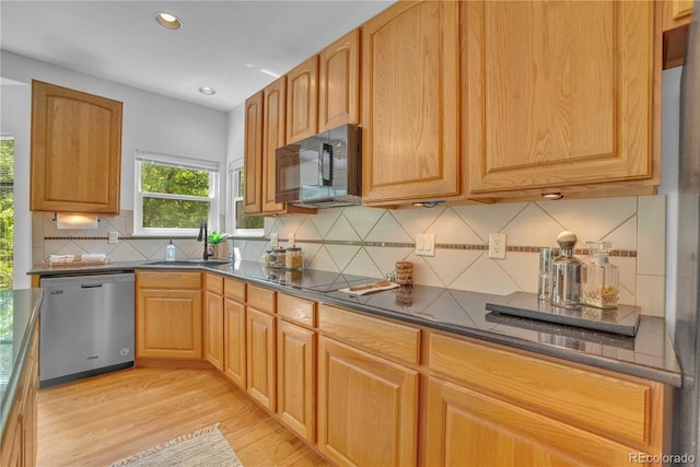 10356 Lions Heart, Lone Tree, CO 80124 - kitchen featuring black appliances, dark countertops, light wood-type flooring, recessed lighting, and decorative backsplash